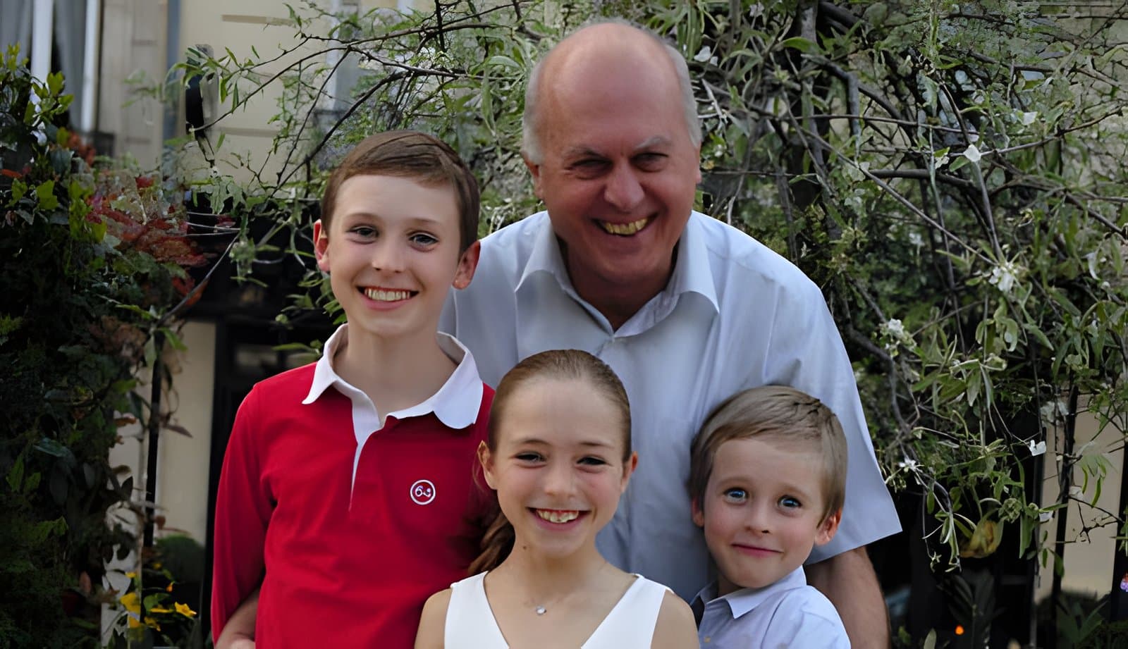 Pierre Angotti souriant, entouré de trois enfants, en extérieur